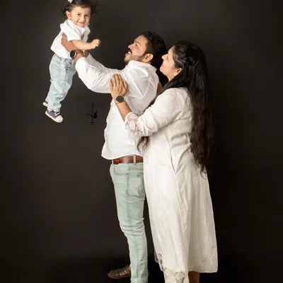A father joyfully lifts his daughter into the air during her first birthday portrait session. The clean black background in my studio ensures that these moments of pure happiness are the center of attention.
