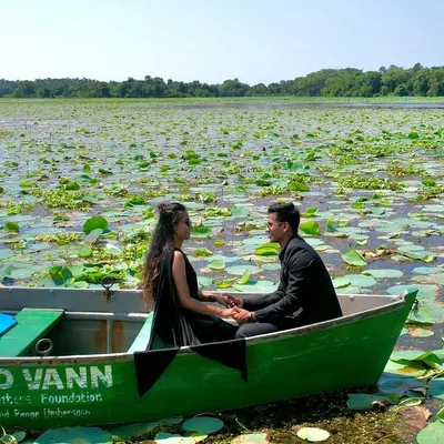 A wide shot of the couple in a boat, surrounded by a vast expanse of lily pads. This photo captures the tranquility and unique beauty of their lakeside pre-wedding shoot.