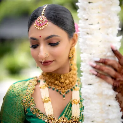 A close-up of the Muhurtham makeup, highlighting the defined eyes, perfectly blended skin, and traditional jewelry like the maang tikka and nose ring. This look is designed to be both elegant and long-lasting.
