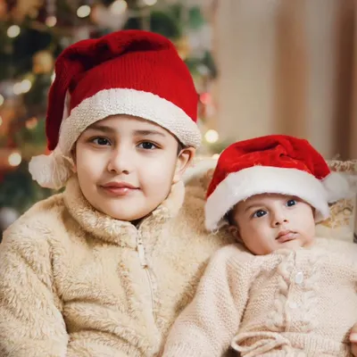 Santa's little helpers, ready for Christmas. This portrait of two brothers in Santa hats captures the sweet innocence and excitement of the holiday season.