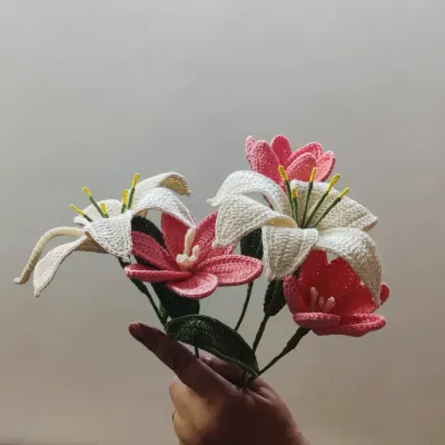 A hand-held bouquet showcasing our intricately crocheted lilies and tulips. The combination of white lilies with pink and coral tulips creates a soft, romantic arrangement that lasts forever.
