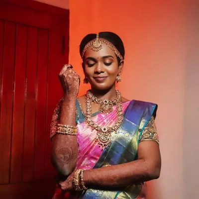 A classic muhurtham look for this beautiful bride. The makeup is kept traditional with defined eyes, a bold lip, and a flawless base that enhances her features and complements her stunning silk saree and gold jewelry.