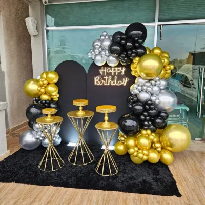 A glamorous black, gold, and silver balloon arch with a neon sign and matching cake stands. This setup is perfect for a sophisticated party on a terrace or patio.