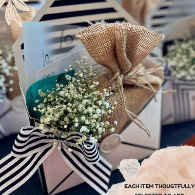 These envelope-styled boxes are perfect for favors or small surprises. Each item inside is thoughtfully selected, and the exterior is adorned with a striped ribbon, baby's breath, and a wax seal for a touch of old-world charm.