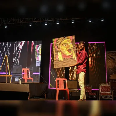 Holding up the completed Kantara speed painting on stage. The energy of the crowd fuels the final, dramatic reveal of the artwork.