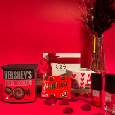 The 'Cozy Delights' hamper is perfect for a romantic night in. It features Hershey's hot chocolate, a heart-themed mug, Nutties, and a set of four luxury perfumes.