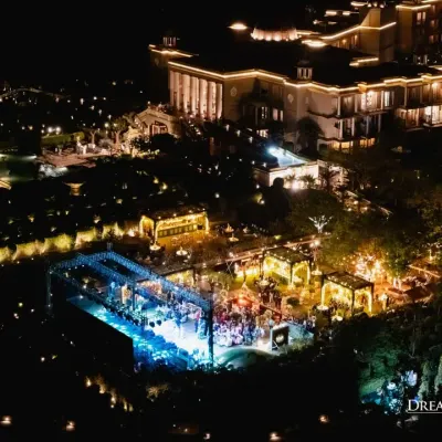 An aerial view of a welcome dinner at Raffles, Udaipur. The setup shows a dynamic layout with a grand stage for performers and elegant lounge areas, all illuminated to create a magical evening.