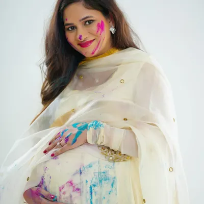 A close-up portrait from our Holi-themed maternity shoot. The bright colors on her face and hands, paired with her joyful smile, perfectly capture the festive and happy spirit of the session.