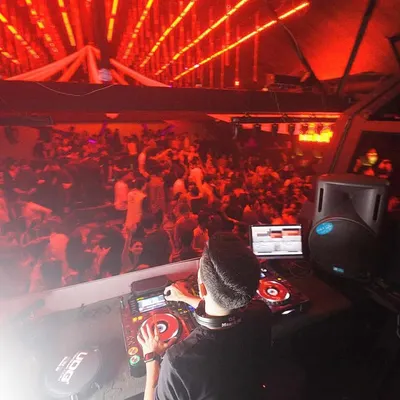 A view from my console overlooking a massive, packed dancefloor bathed in red light. This is the kind of full-house energy I consistently build and maintain throughout my sets.