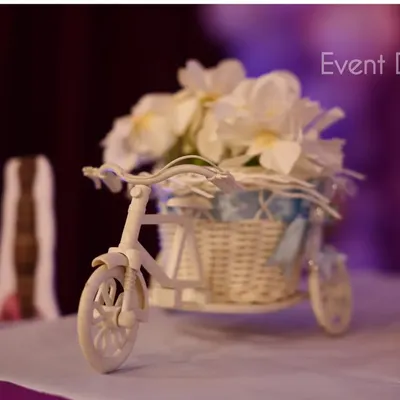 It's all in the details. For a 'Sofia the First' themed birthday party, we included charming props like this miniature white bicycle with a basket of flowers as part of the table centerpiece decor.