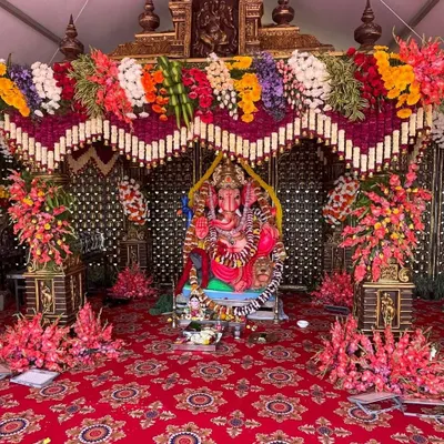 For religious ceremonies like Ganesh Chaturthi or pre-wedding poojas, I create beautiful and respectful decorations. This setup features a grand floral pandal for the Ganesha idol, with vibrant flowers and a traditional red carpet.