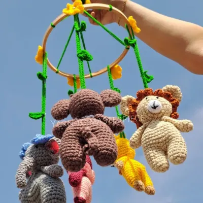 This jungle-themed baby cradle mobile features a whole crew of animal friends, including a lion, monkey, and elephant, hanging from a wooden hoop decorated with vines.