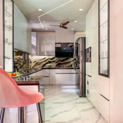 This kitchen was designed with a monochrome theme, featuring high-gloss white cabinets and a striking black and white marble backsplash. The rose pink breakfast chairs add a soft pop of color.