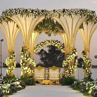 A magnificent wedding mandap with grand, petal-shaped arches adorned with white flowers and gold accents. This opulent design is perfect for a luxurious and unforgettable ceremony.