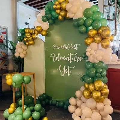 This "Our Wildest Adventure Yet" theme is perfect for adventurous parents-to-be. The setup includes a custom green backdrop and a balloon arch in shades of green, white, and gold, creating a stylish jungle vibe.