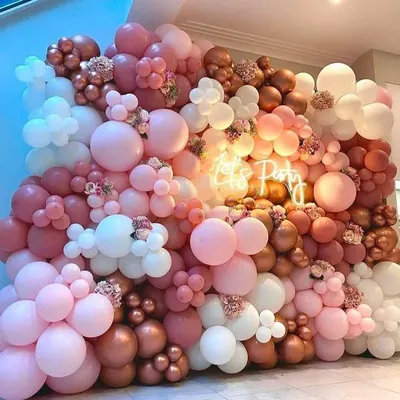 This vibrant "Let's Party" balloon wall is designed to make a statement. The mix of pink, rose gold, and white balloons with a central neon sign creates an energetic and fun photo backdrop.