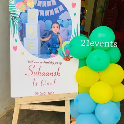 A personalized welcome sign for a first birthday, featuring a photo of the birthday boy and theme elements.