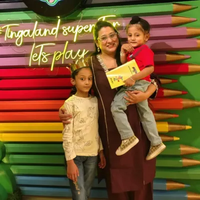 A mother and her two children pose happily, with the kids wearing fun paper crowns.