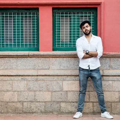 An outdoor portrait of a man standing confidently against a colorful urban wall. This shot showcases my approach to using environmental backdrops to create natural, candid portraits for men's fashion portfolios.