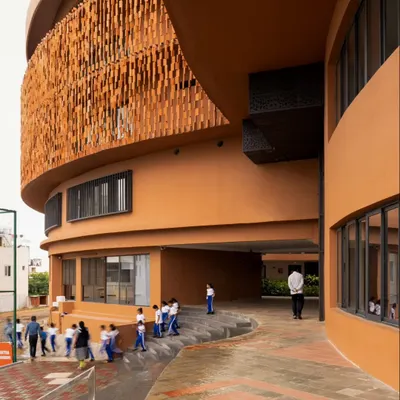 The exterior view of the school highlights its spherical massing and the intricate terracotta screen. The curved form softens the building's scale, while the open ground floor invites movement and interaction, connecting the structure to its surroundings.