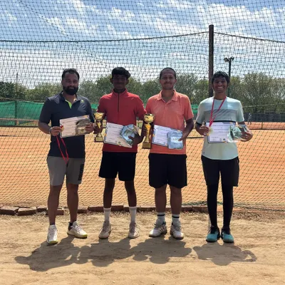 The winner, runner-up, and semi-finalists of our monthly prize money tournament. This group photo shows the top four competitors with their trophies, medals, and certificates on the clay court.