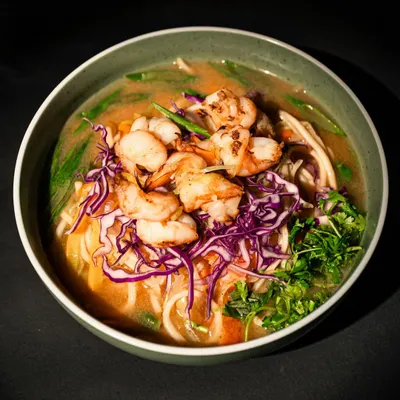 Our Prawns Thukpa is a complete meal in a bowl. It features a steaming, aromatic broth filled with noodles, vibrant vegetables like shredded purple cabbage and fresh greens, and topped with juicy, grilled prawns. It's the ultimate Himalayan comfort food.