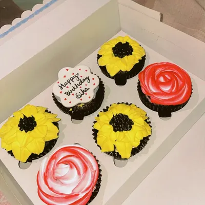 A custom box of six eggless cupcakes designed for a birthday. This set features hand-piped sunflower and rose designs, along with a personalized cupcake with a 'Happy Birthday' message. I can create themed cupcake boxes for any occasion.