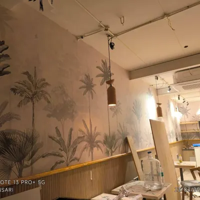 This is a cafe project in Bellandur where I installed a tropical-themed wallpaper above wooden wall paneling. This combination creates a stylish and inviting atmosphere for customers.