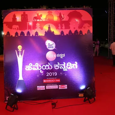 We ensure your brand is front and center. This custom backdrop for the Zee Kannada 'Hemmeya Kannadiga' awards features prominent event and sponsor branding, professionally lit for excellent photo opportunities on the red carpet.