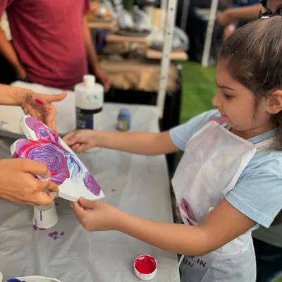 A young artist completely absorbed in her fluid art creation at a flea market event. It's amazing to watch kids explore colors and textures with such freedom.