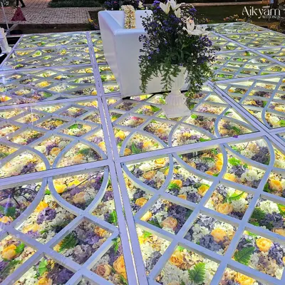 A close-up of our signature illuminated glass floor, filled with a beautiful arrangement of yellow, purple, and white flowers. This detail adds a layer of luxury and enchantment to the wedding aisle.