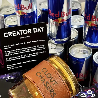 A high-energy PR hamper for 'Clout Chasers' featuring a custom-branded glass tumbler with a leather sleeve, Red Bull cans, and a branded event invitation. This is how we create gifts that perfectly match your brand's vibe.