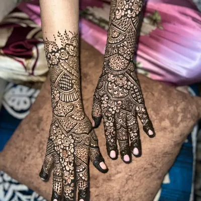 Intricate Indian henna extending to the mid-forearm. This design features a mix of paisleys, florals, and geometric fills.