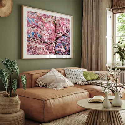 Immerse yourself in the beauty of spring with this vibrant photograph of cherry blossoms. The stunning pinks and blues, captured in a large format print, create a cheerful and breathtaking focal point in this cozy living room.