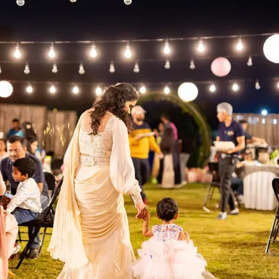 A mother and daughter walking hand-in-hand under a canopy of lights. We design our events to create beautiful, memorable moments like this.