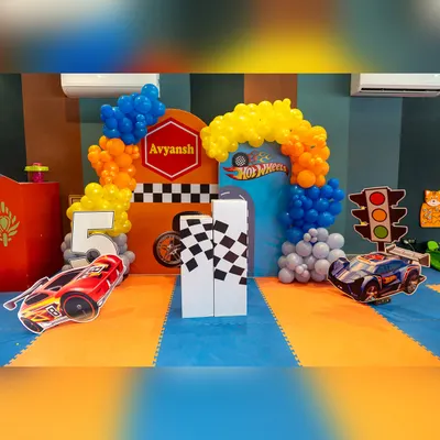 The decor sets the stage for a high-speed adventure. This Hot Wheels party setup features a vibrant backdrop, car cutouts, and a race-track theme.