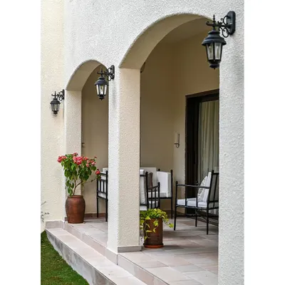 This outdoor seating deck is located across from a courtyard garden, creating a private oasis. The arched colonnade is a classic Spanish architectural feature, and the traditional black lanterns enhance the home's exterior charm.