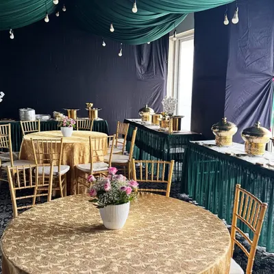 A complete view of our event styling. We coordinated the gold brocade tablecloths and chiavari chairs with the emerald green ceiling drapes and buffet skirting to create a rich, celebratory atmosphere.