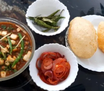 Our weekend special: home-cooked Chole Bhature. The spicy chole masala is served with fluffy bhature, pickled onions, and fried green chillies.