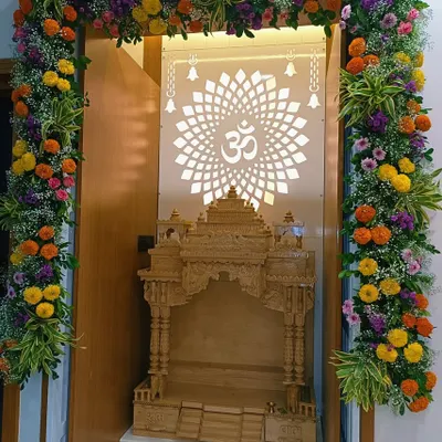 We decorated this beautiful home mandir with a full floral arch made of bright marigolds, purple statice, and baby's breath. The design complements the intricate wooden temple and the backlit 'Om' panel, creating a truly divine prayer space.