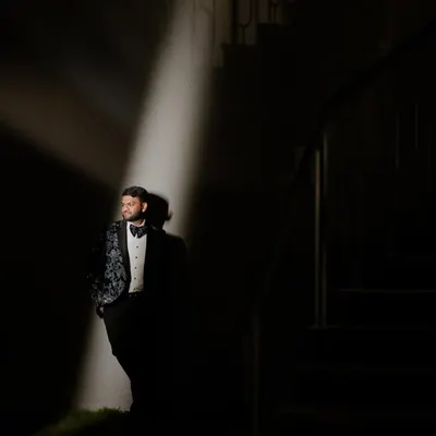 A dramatic portrait of the groom, Shivam, using a single spotlight to create a cinematic, high-contrast look before his cocktail party.