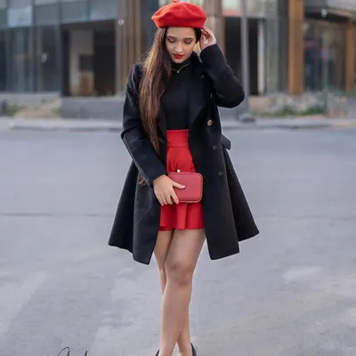 A full-length look capturing the essence of Parisian fashion. The combination of a black trench coat over a red skirt, paired with a matching beret and clutch, creates a complete and polished style statement.