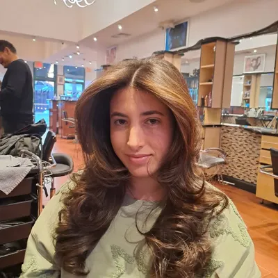 A classic layered haircut finished with a bouncy, voluminous blowout. This style adds body and movement to long hair.