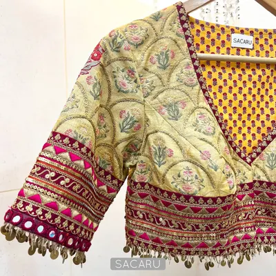 An artistic expression through fabric and embellishment. This blouse combines multiple prints and is finished with brass sequin hand-embroidered details.
