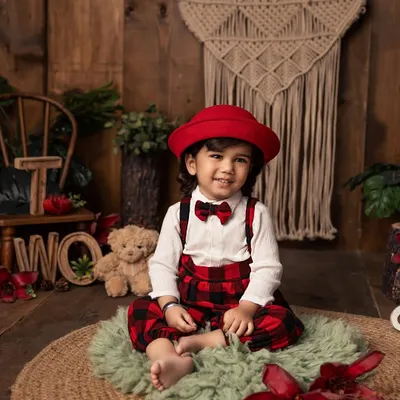 Two years old and full of style! This little gentleman, dressed in plaid overalls and a smart red hat, is celebrating his second birthday with a charming and rustic-themed portrait session.