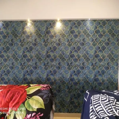 A stylish bedroom accent wall featuring a blue and grey geometric wallpaper with a subtle texture. The pattern adds a modern touch behind the bed.