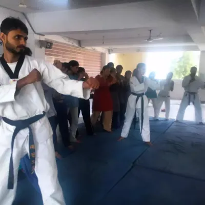 An instructor leads a self-defense workshop for women, demonstrating a blocking technique. Our workshops focus on practical, easy-to-learn moves for real-world situations.