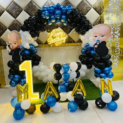 A classic Boss Baby theme for a first birthday. This setup includes a balloon arch in blue, black, and white, character cutouts, a 'Happy Birthday' neon sign, and a light-up number '1'.