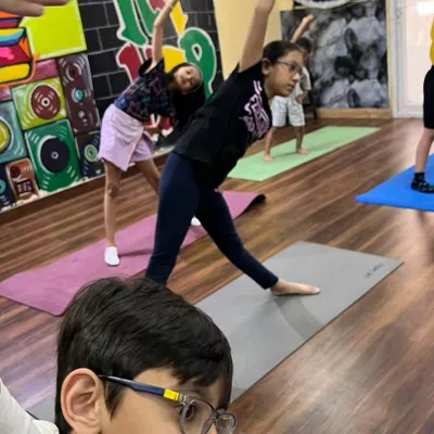 The triangle pose, or Trikonasana, is great for stretching and balance. Here, the kids are learning the pose together during a summer yoga session.