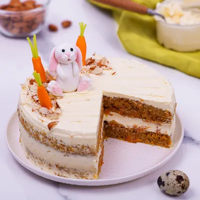 Our Easter Carrot Cake is a classic, beautifully decorated with a fondant bunny, edible carrots, and toasted almonds.